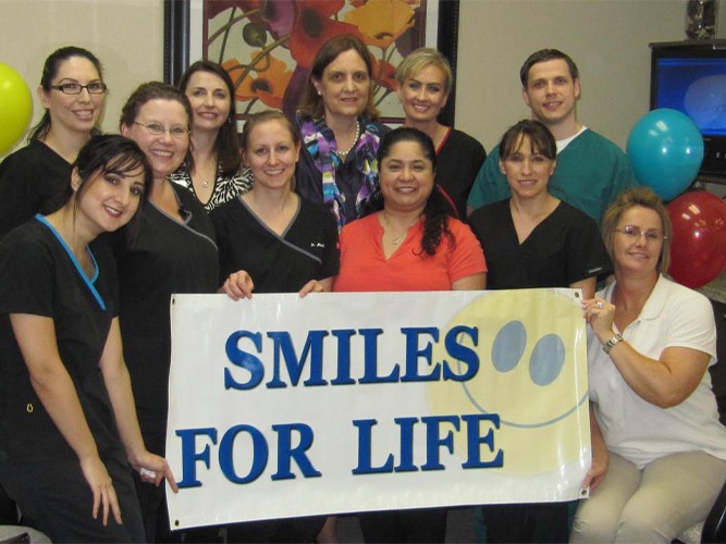 Dental team holding up smiles for life sign