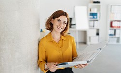 Smiling woman holding binder in office
