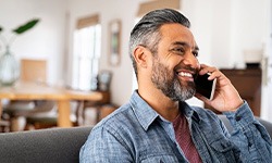Man smiling while talking on phone at home