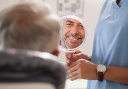 Man looking at his smile after full mouth reconstruction