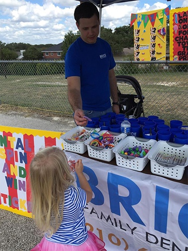 Dentist giving child a prize at community event