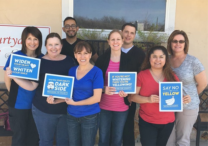 Dental team holding up signs outside of dental office