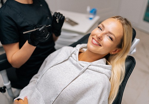 Woman in grey sweater smiling in treatment chair