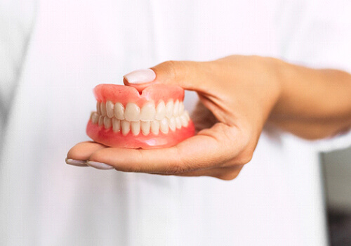 Dentist holding full dentures in San Antonio