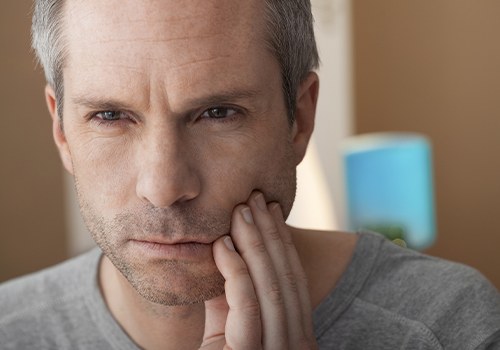 Man in need of emergency dentistry holding cheek