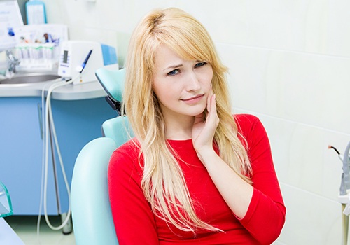 Woman at emergency dentistry appointment holding cheek