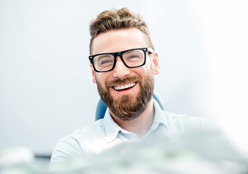 Man with glasses smiling in dental chair