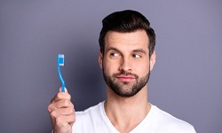 Man holding a toothbrush from implant dentist in San Antonio