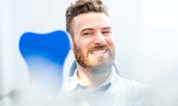 Man admiring his new smile after dental implant surgery in San Antonio