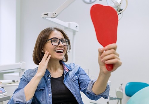 young woman admiring her new dental implants in San Antonio