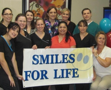Brice Dental team holding a Smiles for Life banner