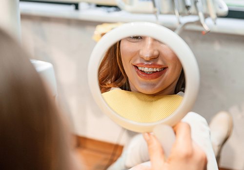 Patient with clear aligners smiling at reflection in mirror
