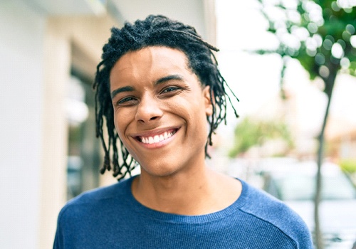 A young man wearing a blue shirt and showing off his perfectly aligned smile thanks to Invisalign in San Antonio