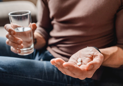 Close-up of person holding pills and glass of water