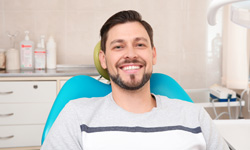 Male dental patient sitting in dental chair smiling