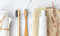 Two toothbrushes and one toothpaste bottle siting on a countertop 