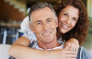 Older man and woman sharing smiles after replacing missing teeth