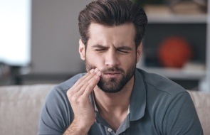 Man in need of emergency dentistry holding cheek