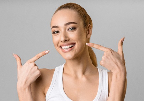 woman pointing to smile after getting veneers in San Antonio