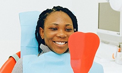 Smiling woman looking in dental mirror