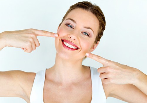 Woman pointing to smile after teeth whitening