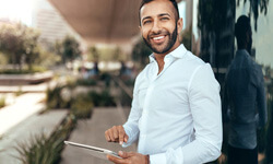 man outside holding a tablet and smiling