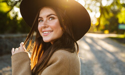 woman with hat standing outside and smiling