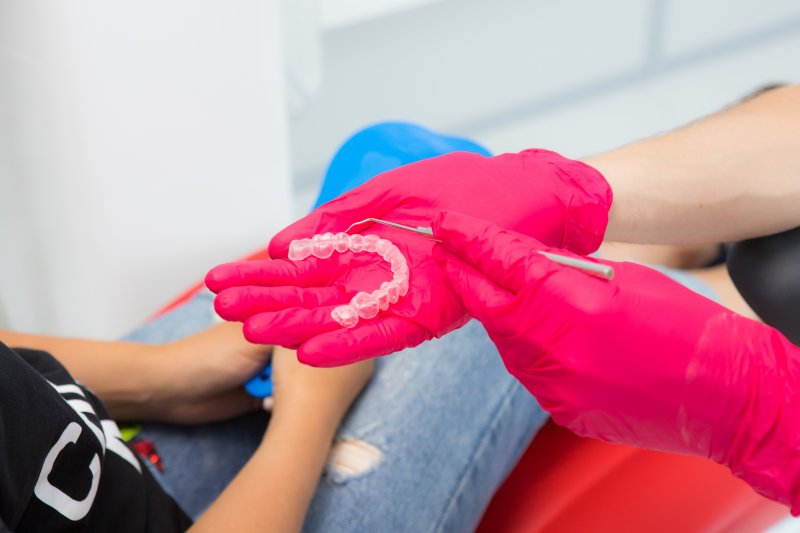 Dentist showing patient Invisalign aligner