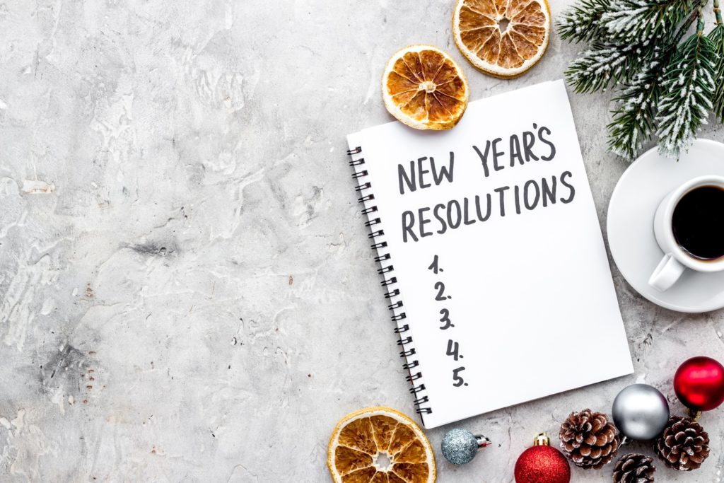 New Year's Resolutions on notepad next to festive decor