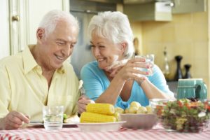 Older couple with dental implants enjoying various summertime foods.