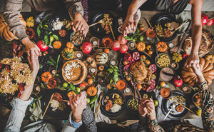 Family holding hands over Thanksgiving food