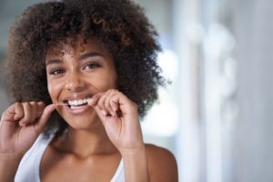 woman smiling while flossing her teeth