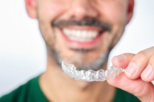 Man smiling while putting in his Invisalign trays